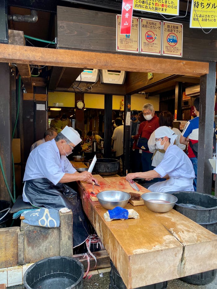 Chefs preparing fresh fish in a bustling Japanese market.